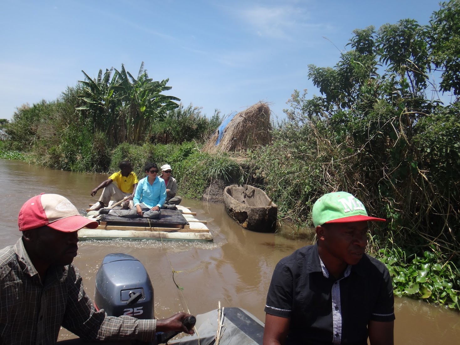 The coring raft under tow on a wetland channel, papyrus and banana on the bank