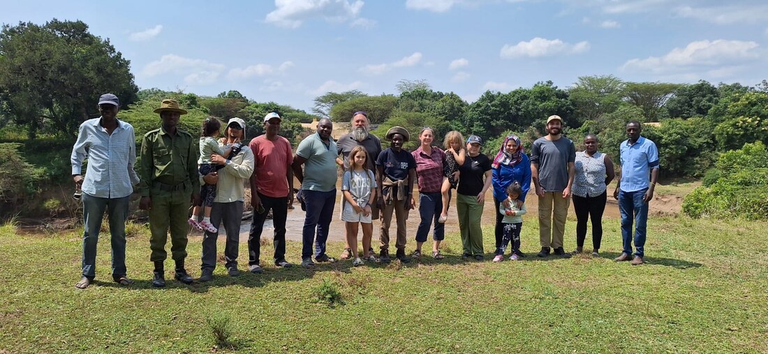 Field crew and their families on the riverbank with a ranger